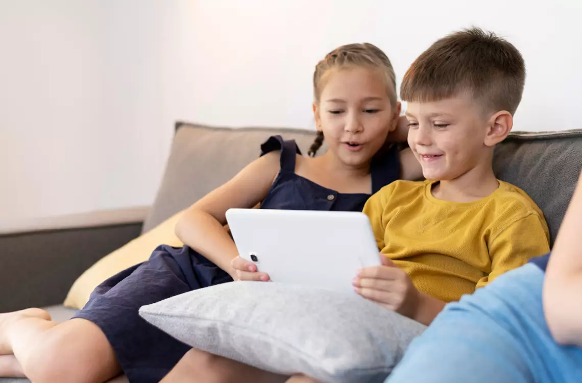 Deux enfants sur un canapé devant une tablette