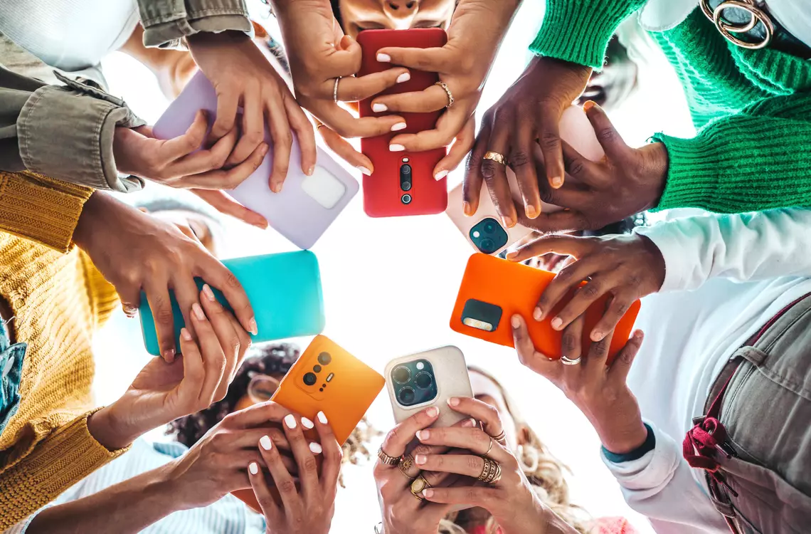 plusieurs jeunes en rond avec leur smartphone en main (vue depuis dessous)