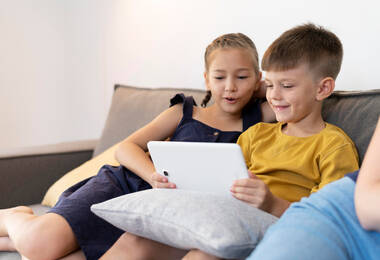 Deux enfants sur un canapé devant une tablette