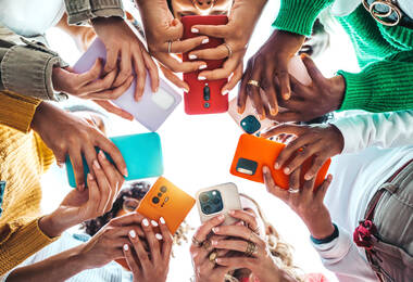 plusieurs jeunes en rond avec leur smartphone en main (vue depuis dessous)